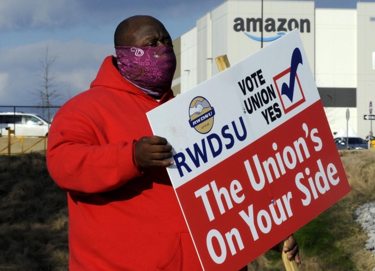 A man holds a pro-union sign outside an Amazon facility.