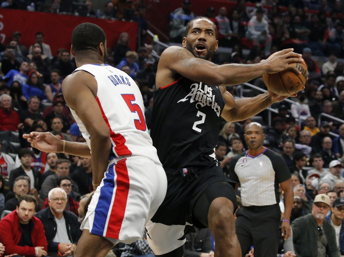 Clippers forward Kawhi Leonard gathers the ball on a drive to the basket against Pistons guard Alec Burks.