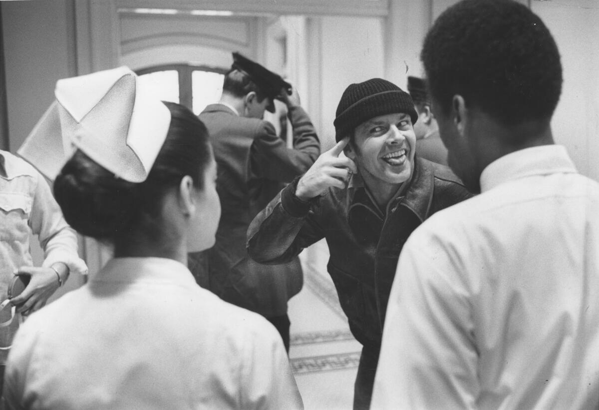 A black-and-white photo of a man acting crazy in front of white-coated medical personnel.