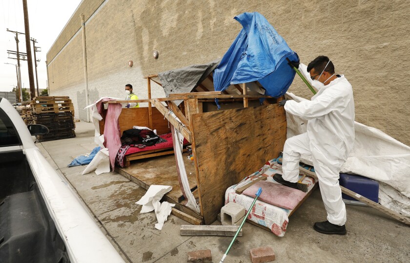  Jesus Sanchez, left, and Javier Villarreal of L.A.'s Bureau of Sanitation participate in the cleanup of a homeless encampment in May in South Los Angeles.