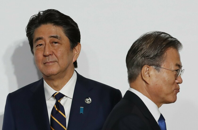 South Korean President Moon Jae-in, right, walks by Japanese Prime Minister Shinzo Abe at a welcome and photo session at the G-20 leaders summit in Osaka last month.