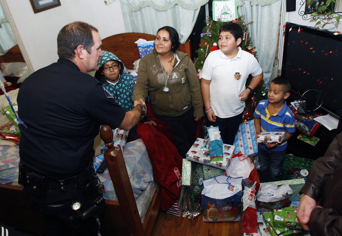 Officer Ben Bateman shakes hands with Guadalupe Ramirez with her children David, 9, Christopher, 10, and Alejandro, 6, as part of the "Cops for Kids" toy donation, organized by the Glendale Police Officers Association in Glendale on Thursday, December 19, 2013.