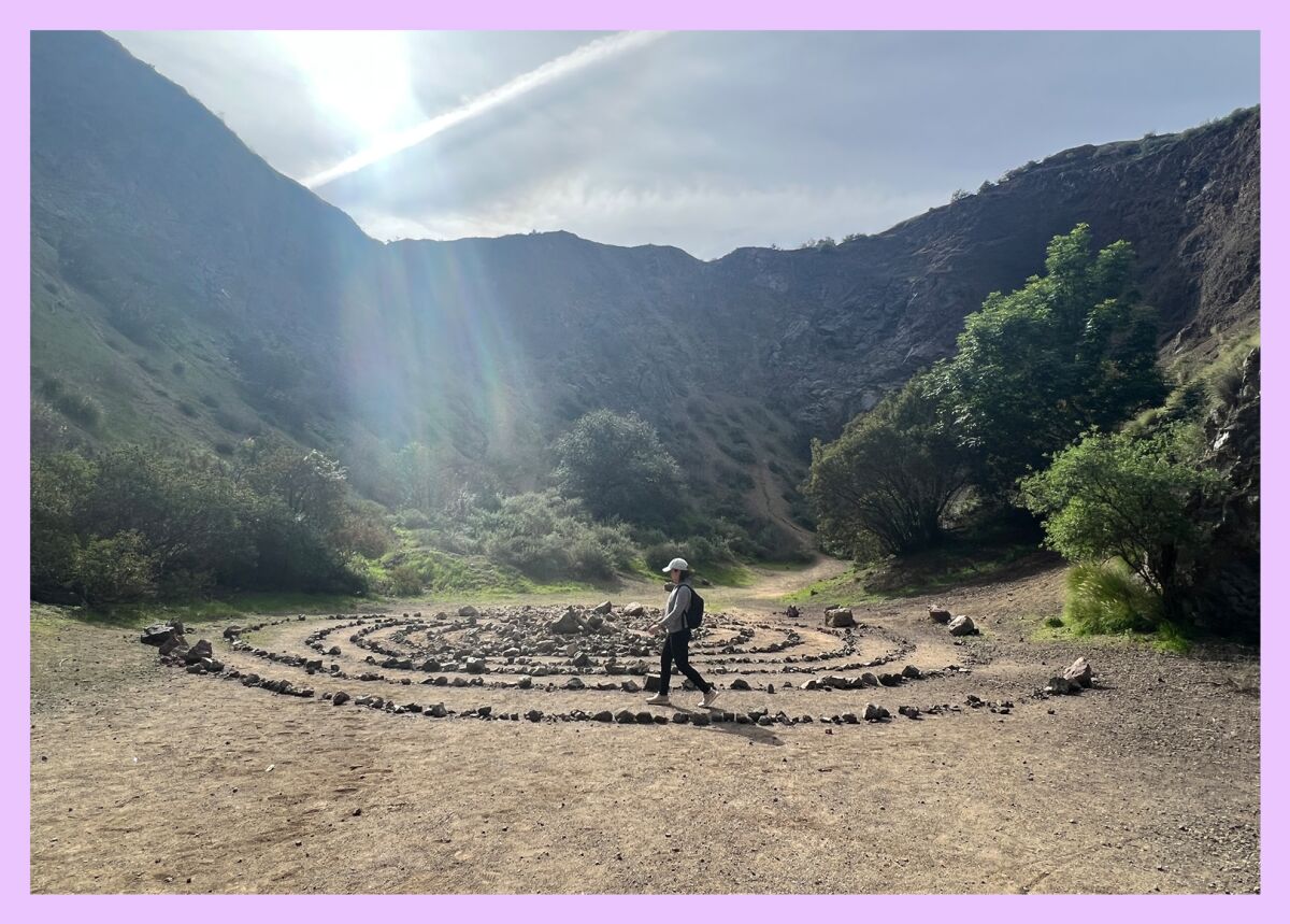 A person walks a meditation labyrinth made of rocks.