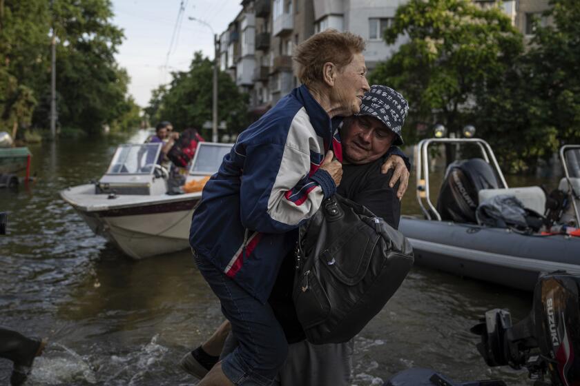 A volunteer carries a woman as she is evacuated from a flooded Kardashynka village of the left bank Dnipro river, in Kherson, Ukraine, Friday, June 9, 2023. Many small boats carrying volunteers and Ukrainian soldiers have shuttled across from Ukrainian-held areas on the west bank to rescue desperate civilians stuck on rooftops, in attics and in other areas amid the deluge.(AP Photo/Evgeniy Maloletka)