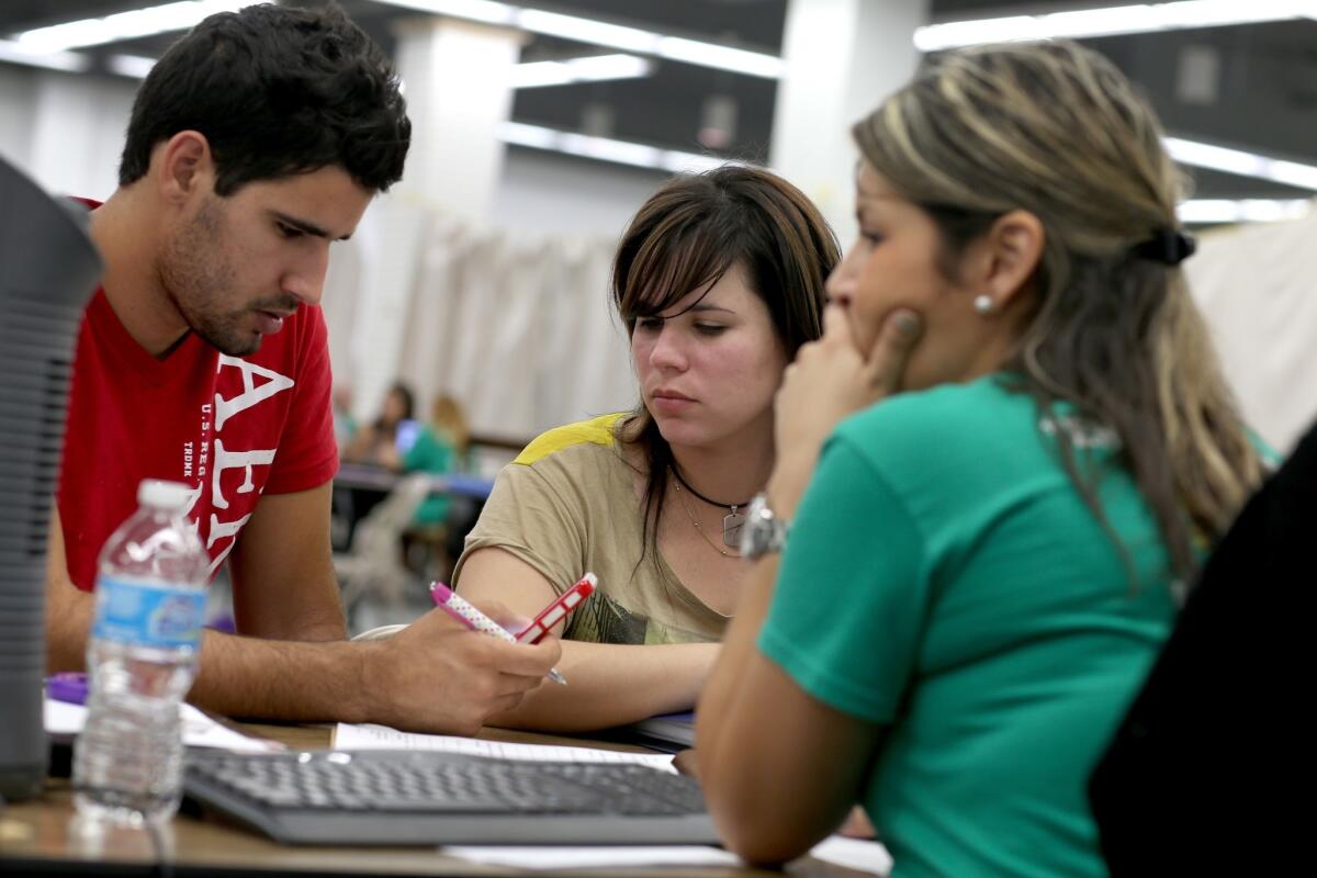 Jose Villanueva, left, and Doraisy Avila sit with Maria Gabriela, an agent from Sunshine Life and Health Advisors, as they discuss pricing plans available under the Affordable Care Act at the Mall of Americas in Miami.