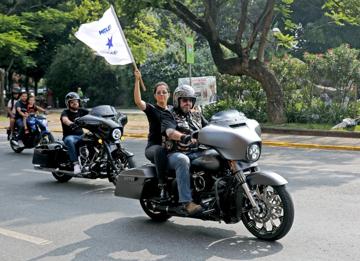Guatemala vice presidential candidate Maximo Santa Cruz rides through Guatemala City as his passenger waves a flag 