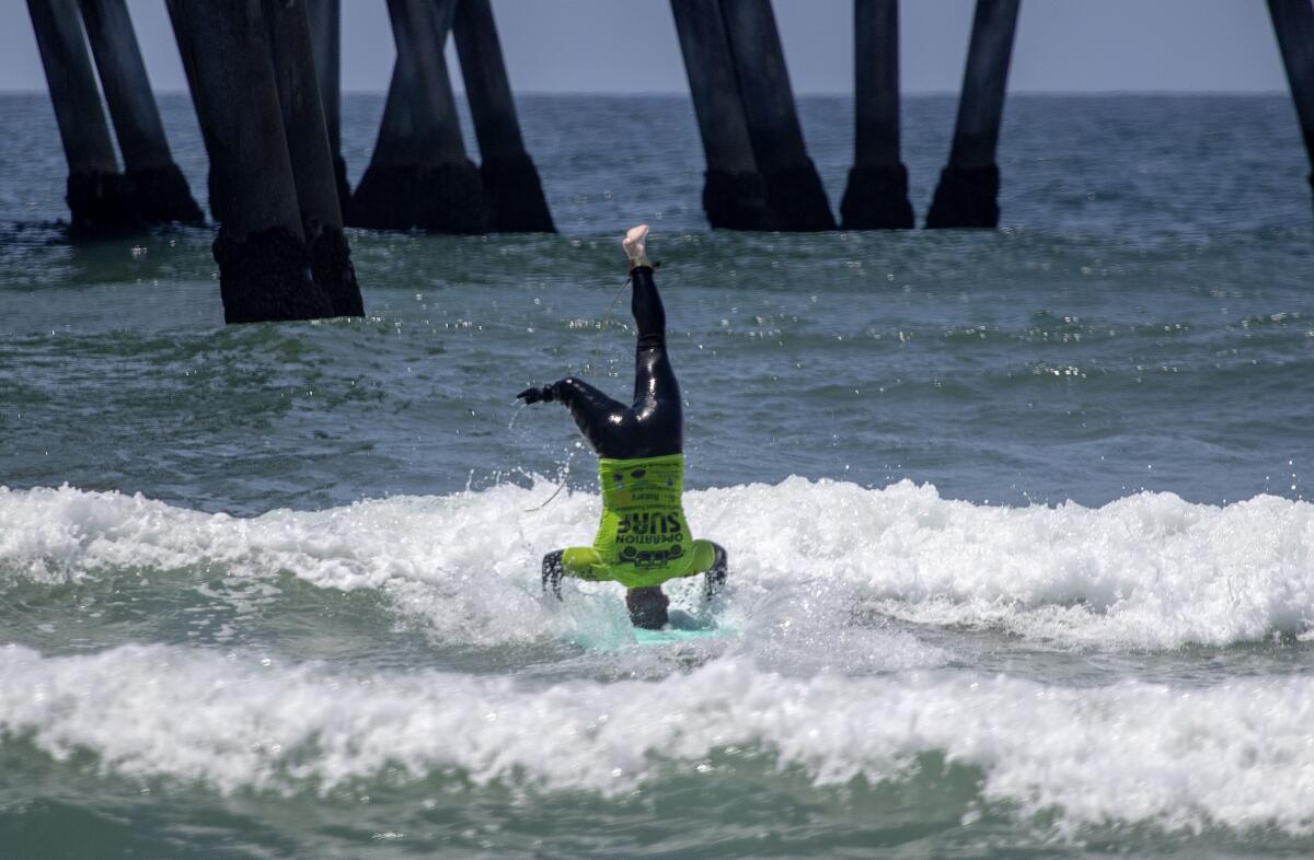 U.S. Army veteran Stephen Peterson, who lost his leg to an IED in Afghanistan in 2011, does a headstand while surfing in Huntington Beach.