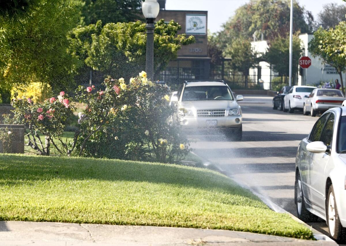 Sprinklers water a lawn at a home in the 1800 block of Screenland Drive near Burbank Middle School in Burbank on Thursday, August 15, 2013.