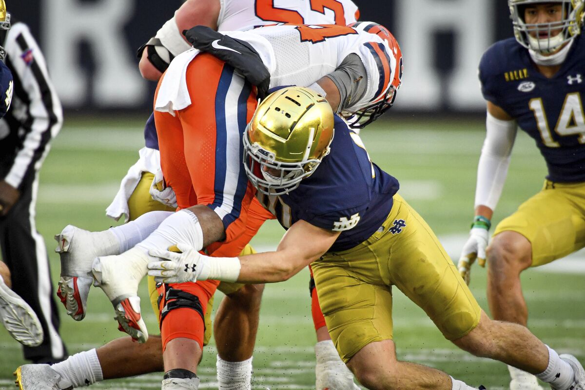 FILE - Syracuse running back Sean Tucker (34) is tackled by Notre Dame linebacker Drew White (40) in the second half of an NCAA college football game in South Bend, Ind., in this Saturday, Dec. 5, 2020, file photo. Marcus Freeman believes the best thing he can do as Notre Dame’s new defensive coordinator is to get out of the way of his players. (Matt Cashore/Pool Photo via AP, File)