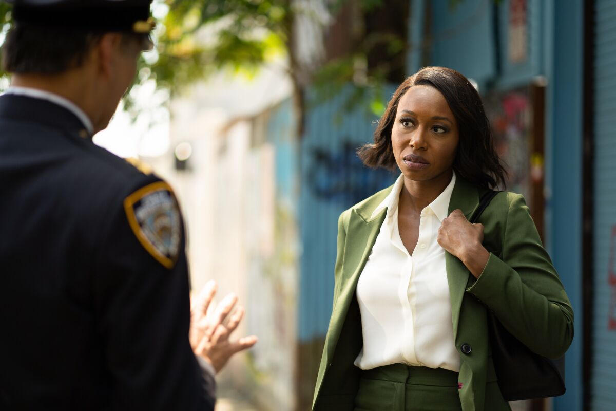 A woman in a green suit with a purse slung over her shoulder