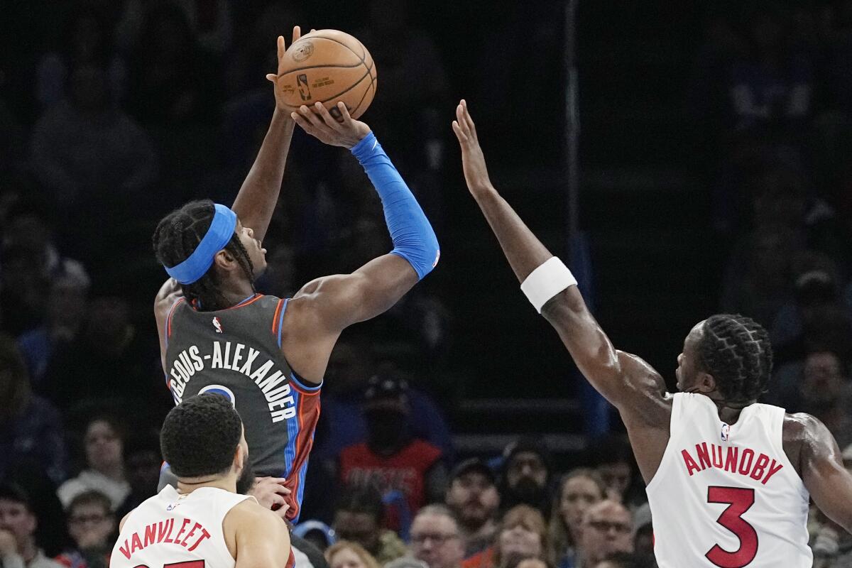 Oklahoma City Thunder guard Shai Gilgeous-Alexander, top left, shoots in front of Toronto Raptors guard Fred VanVleet, bottom left, and forward O.G. Anunoby (3) in the first half of an NBA basketball game Friday, Nov. 11, 2022, in Oklahoma City. (AP Photo/Sue Ogrocki)