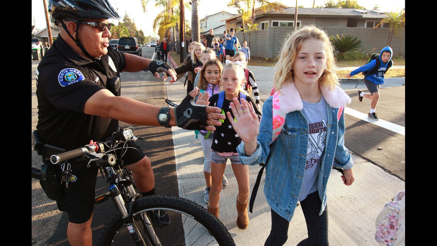 School Resource Officer Jose Torres high-fives Kaiser Elementary School students during Walk to School Day on Wednesday in Costa Mesa.