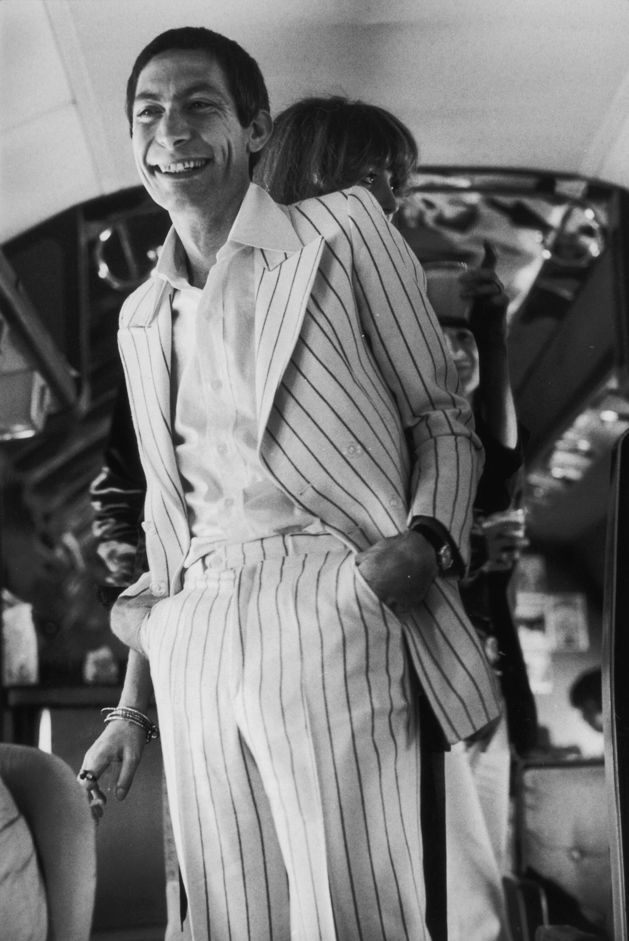 A black-and-white photo of Rolling Stones drummer Charlie Watts in a striped suit.