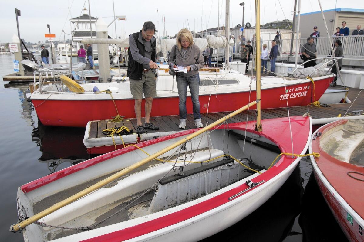 Richard Mays and Mel Fitch check out a sailboat during an auction of abandoned vessels in Newport Beach on Dec. 5.