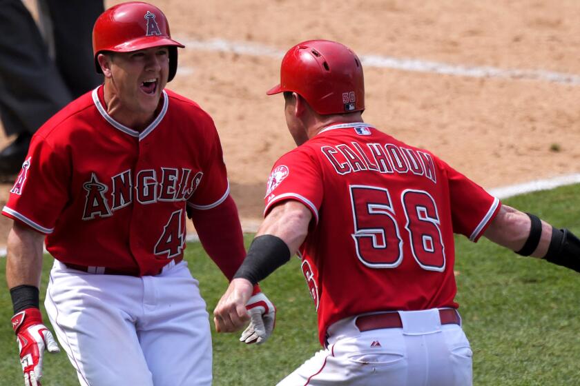 Angels right fielder Kole Calhoun (56) celebrates with teammate Daniel Robertson after scoring the winning run against the Mariners on a wild pitch in the 10th inning Sunday in Anaheim.