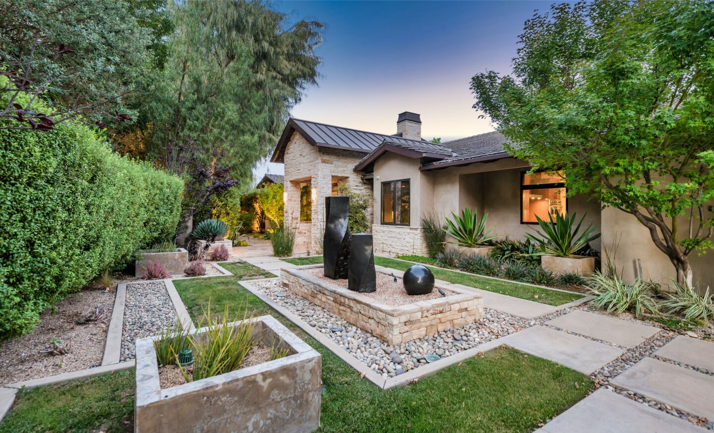 The courtyard with a view of the home, trees and grass.