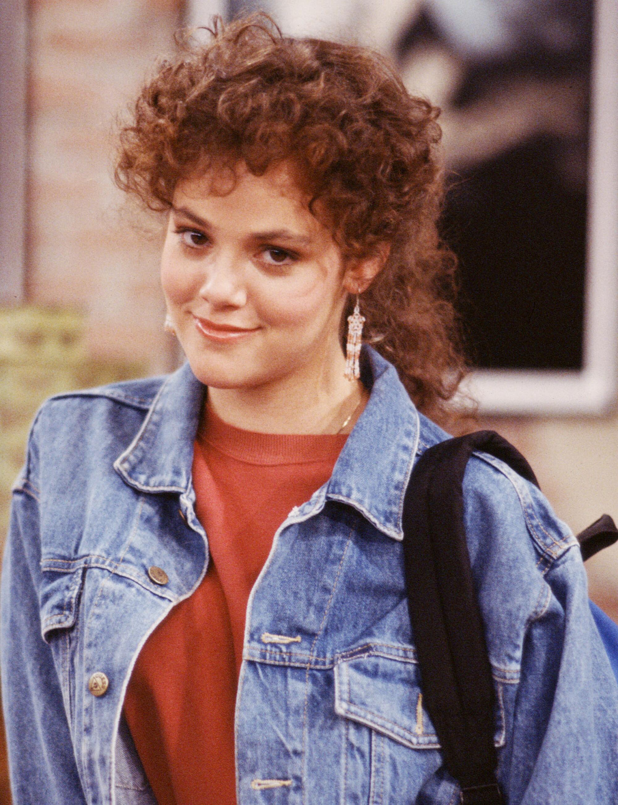 A woman with curly hair and a denim jacket.