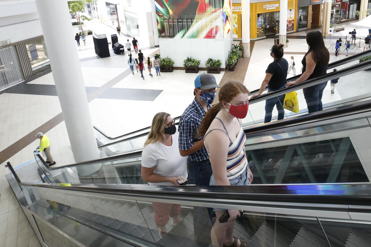 People wearing masks take an escalator