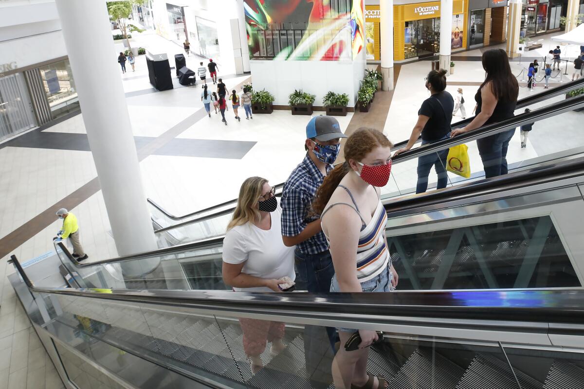 People wearing masks take an escalator 