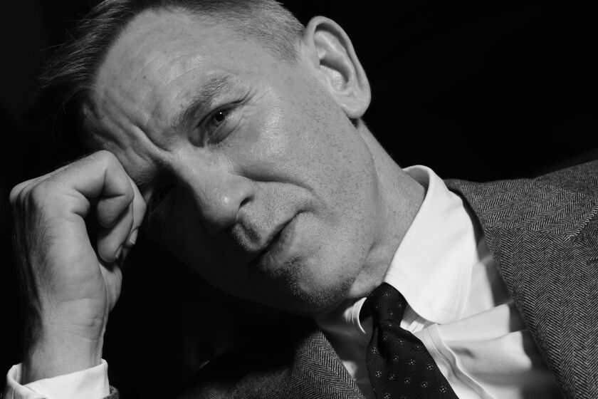 A black-and-white photo of Daniel Craig leaning his head on his fist