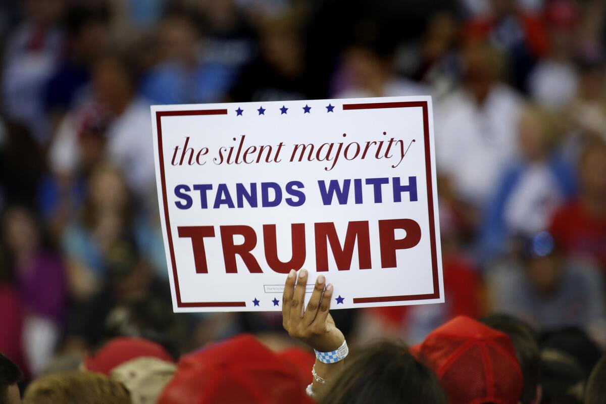 A Trump supporter holds a sign saying the "silent majority" at a rally in 2016. 