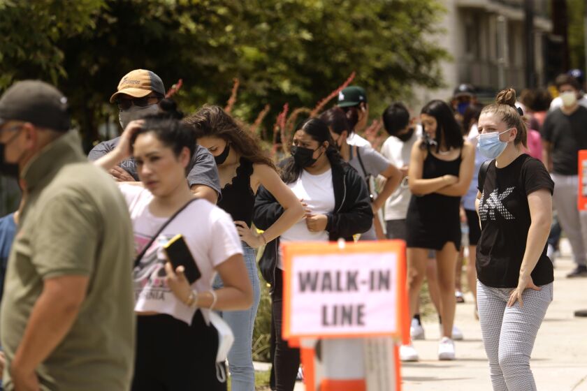 NORTHRIDGE, CA - AUGUST 11, 2021 - - Students, along with their parents, wait in line to be tested for COVID-19 at Northridge Middle School in Northridge on August 11, 2021. Some parents also received the test for COVID. LAUSD has the most robust COVID-19 testing protocol in California, is requiring all students and teachers to be tested weekly. California could be the first state in the U.S. with a teacher vaccine mandate. Gov. Newsom announced today that all teachers and school staff in the state will be required to get vaccinated or submit to weekly testing. (Genaro Molina / Los Angeles Times)