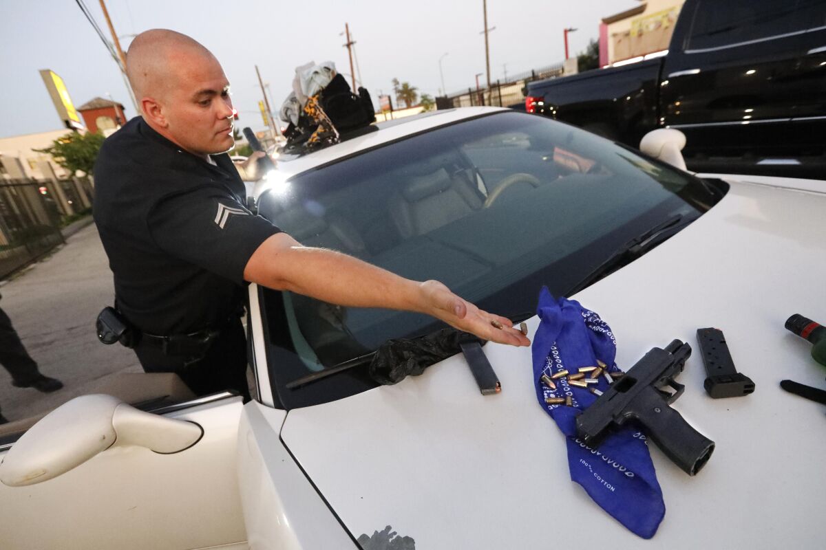 Guns and bullets displayed by a police officer on the hood of a car