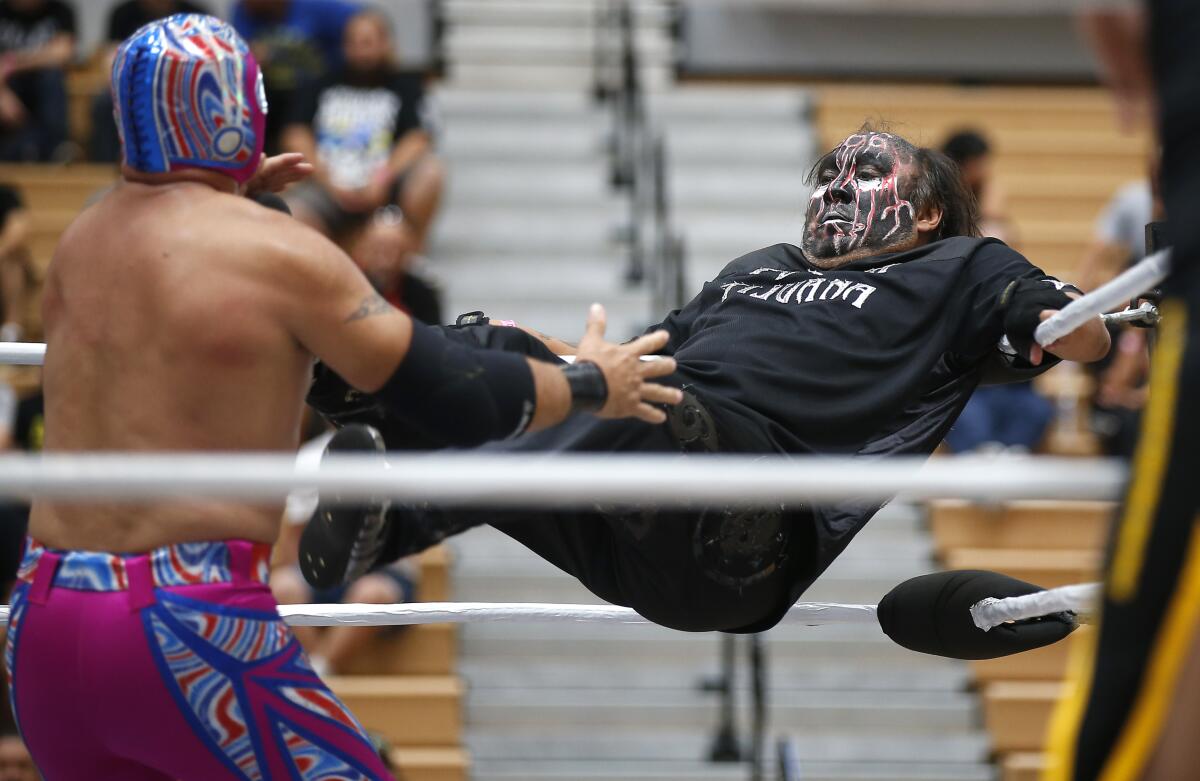 Damián 666, right, kicks Piloto Suicida during a lucha libre match at Expo Lucha at Harry West Gymnasium at San Diego City College on August 18, 2019. The three-day event featured live wrestling, along with meet and greets and vendor booth.