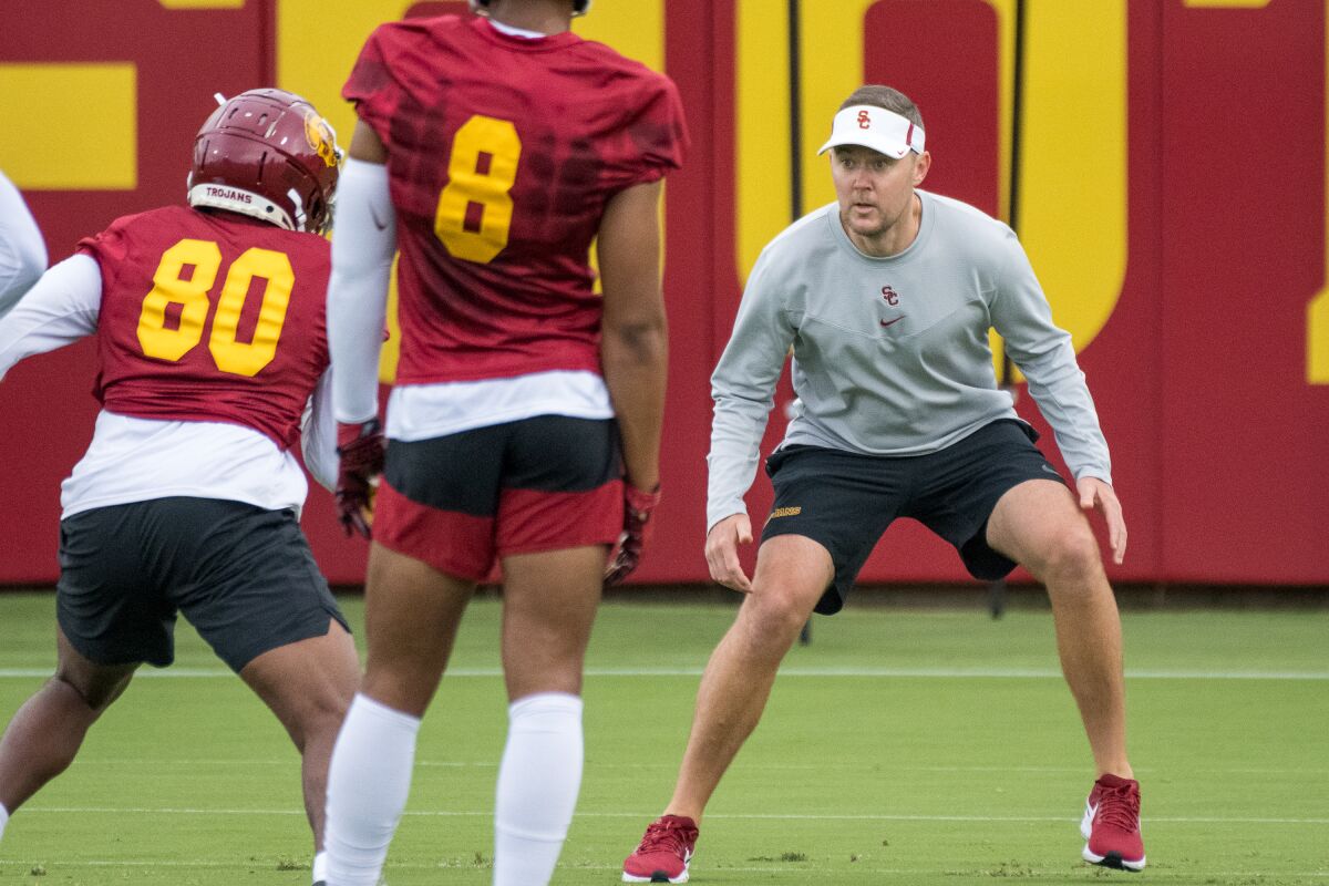 USC head coach Lincoln Riley gets in a defensive stance as he works with receivers at practice.