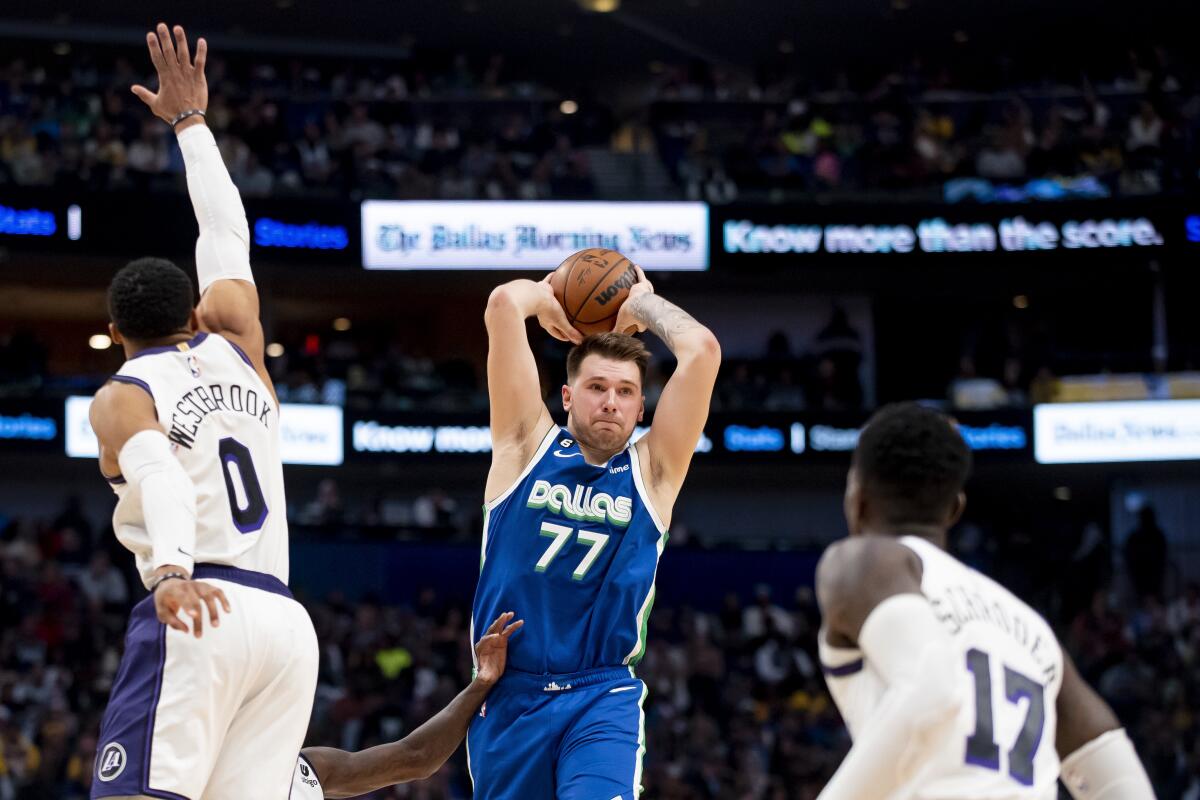 Mavericks guard Luka Doncic prepares to pass as Lakers guards Russell Westbrook (0) and Dennis Schroder defend him.