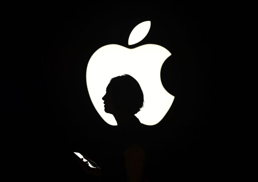 A reporter walks by an Apple logo during a media event in San Francisco, California on Sept. 9, 2015.