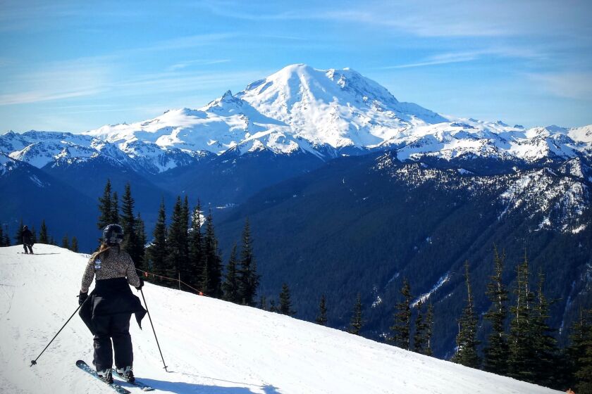A skier takes in the view of Mt. Rainier just 14 miles to the south while following a traverse near the top of Crystal Mountain.