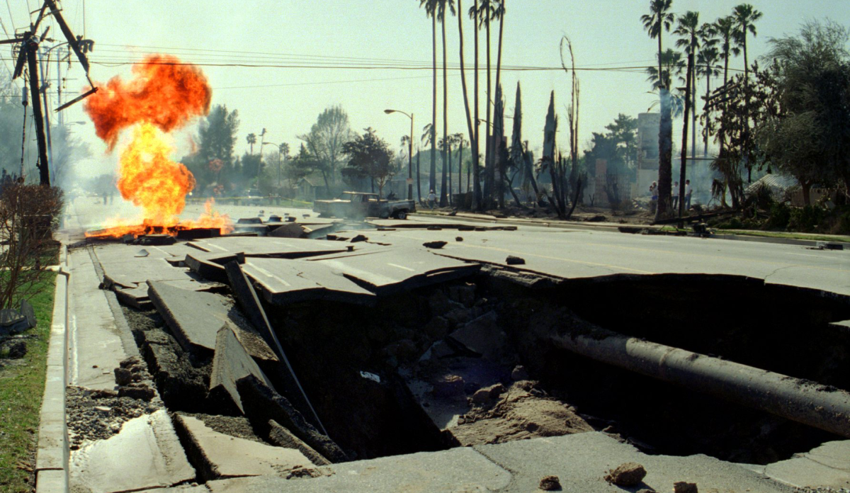 Flames billow from a ruptured gas main beyond a crater in Granada Hills after the 1994 Northridge earthquake. (Los Angeles Times)