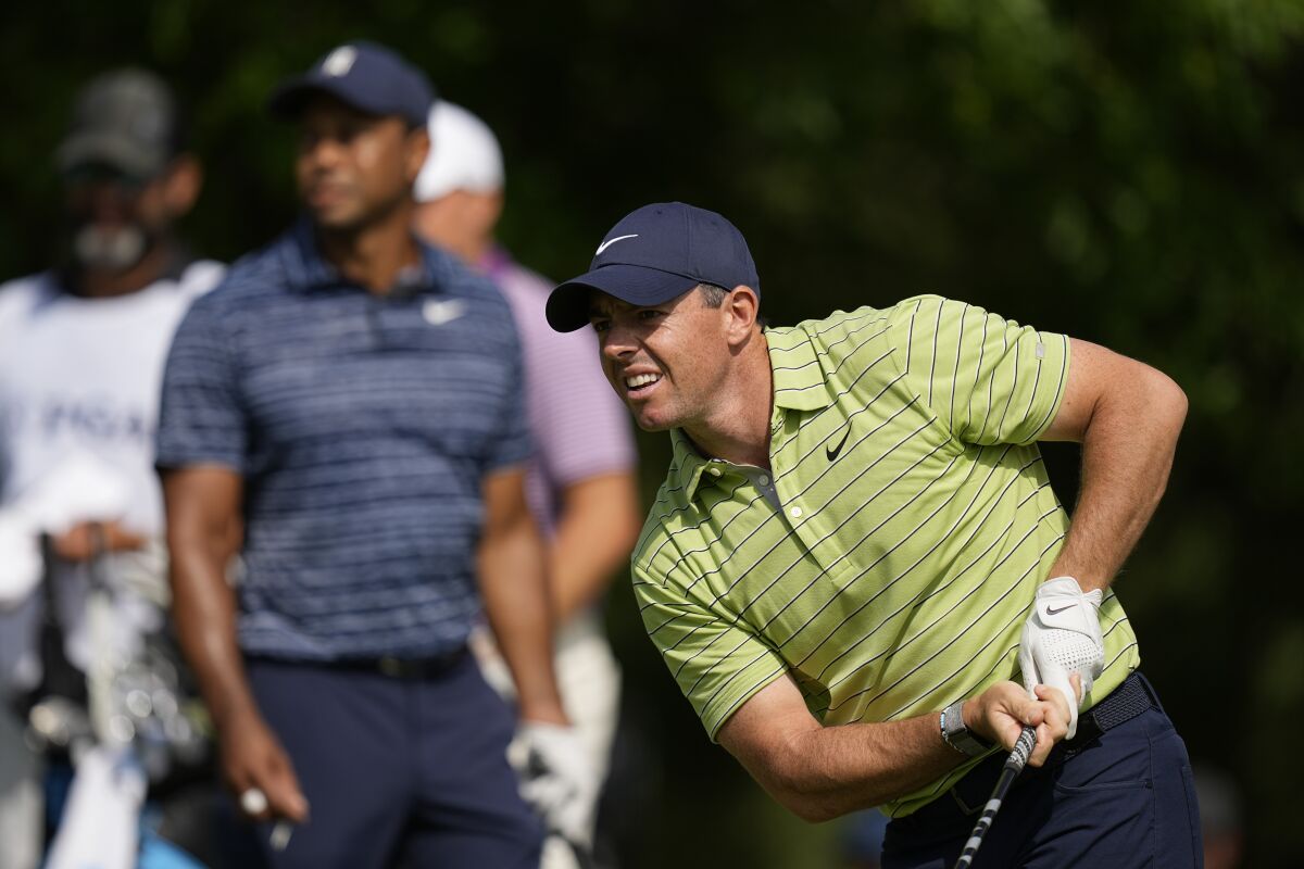 Rory McIlroy, right, watches his shot from the 17th tee as Tiger Woods looks on.