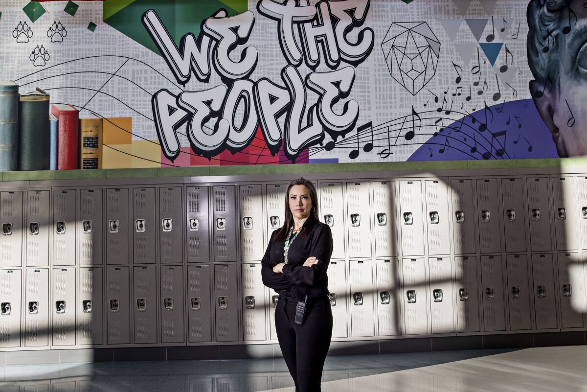 D. Rae Garrison, the principal of West Jordan Middle School in Utah,  in front of a "We the People" sign over lockers
