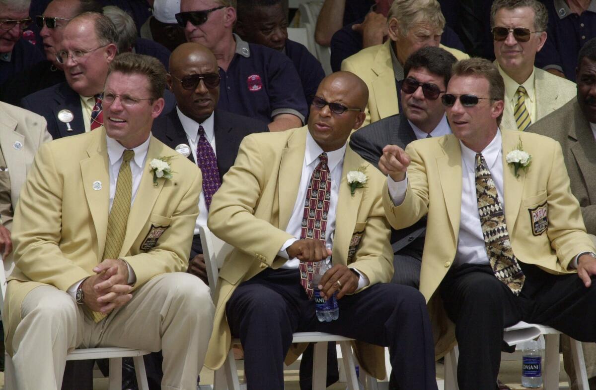 Howie Long, Ronnie Lott and Joe Montana watch a video presentation during their enshrinement into the Pro Football Hal of Fame on July 29, 2000.