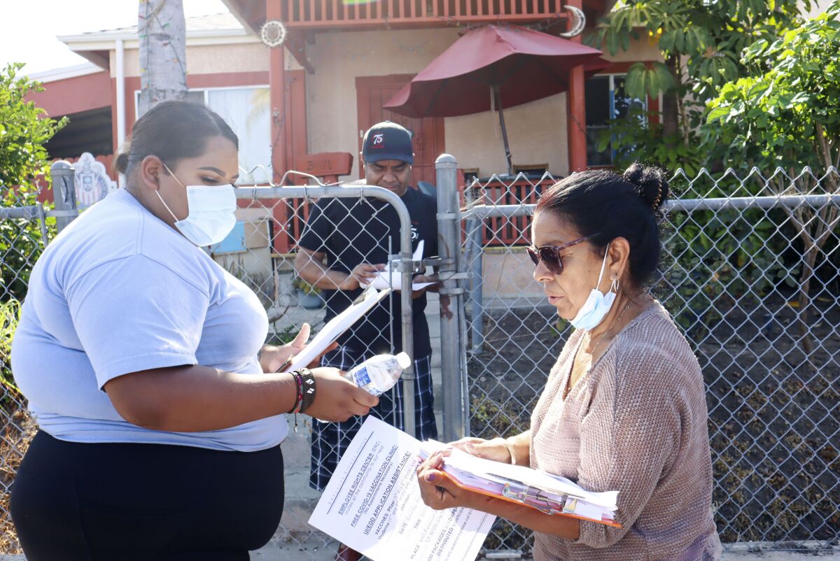 Volunteers Yesenia Luco and Antonia Galindo from the Employee Rights Center hand out information on  the COVID vaccine.
