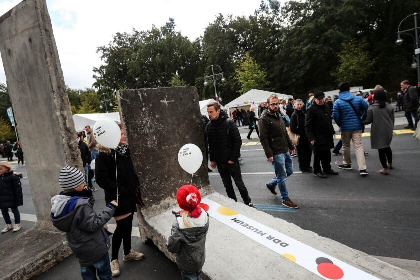 Mandatory Credit: Photo by FELIPE TRUEBA/EPA-EFE/REX (9911708br) A family stands around a former part of the Berlin Wall displayed near the Brandenburg Gate during the festivities of the German Day of Unity, in Berlin, Germany, 03 October 2018. The German Day of Unity, celebrating the 28th anniversary of the reunification of East and West Germany in 1990, is followed in many cities countrywide. The official national ceremony and main events of this year are taking place in Berlin. German Day of Unity in Berlin, Germany - 03 Oct 2018 ** Usable by LA, CT and MoD ONLY **