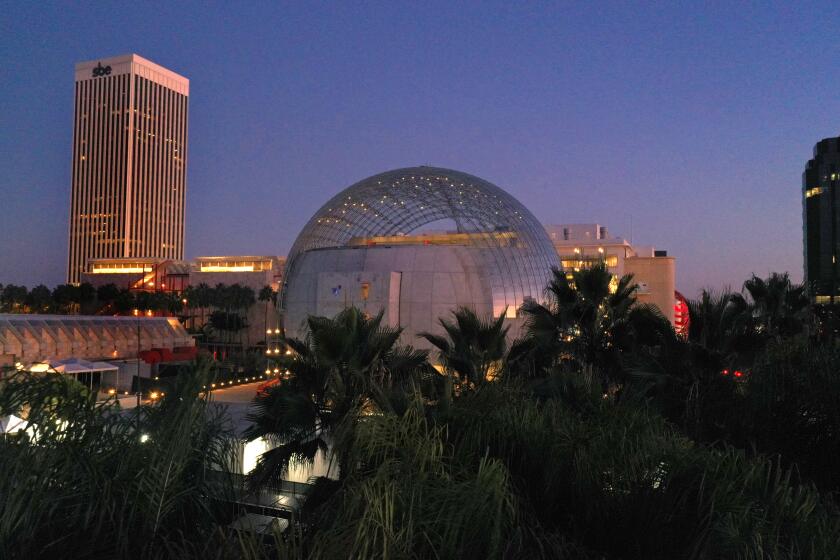 The Academy Museum's ball-shaped Geffen Theater is seen at dusk, fringed by palms