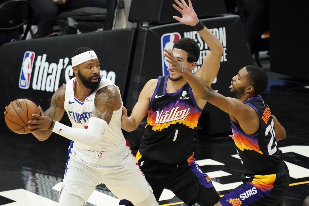 Clippers forward Marcus Morris Sr. looks to pass under pressure from Suns guard Devin Booker (1) and forward Mikal Bridges.