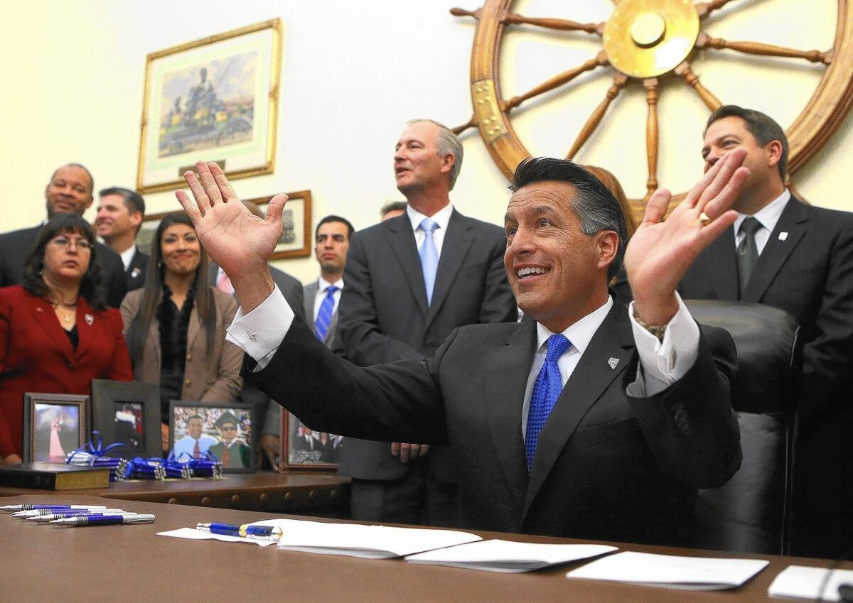 Surrounded by lawmakers and staff members, Nevada Gov. Brian Sandoval signs into law an unprecedented package of incentives to bring Tesla Motors' $5-billion battery factory to the state.
