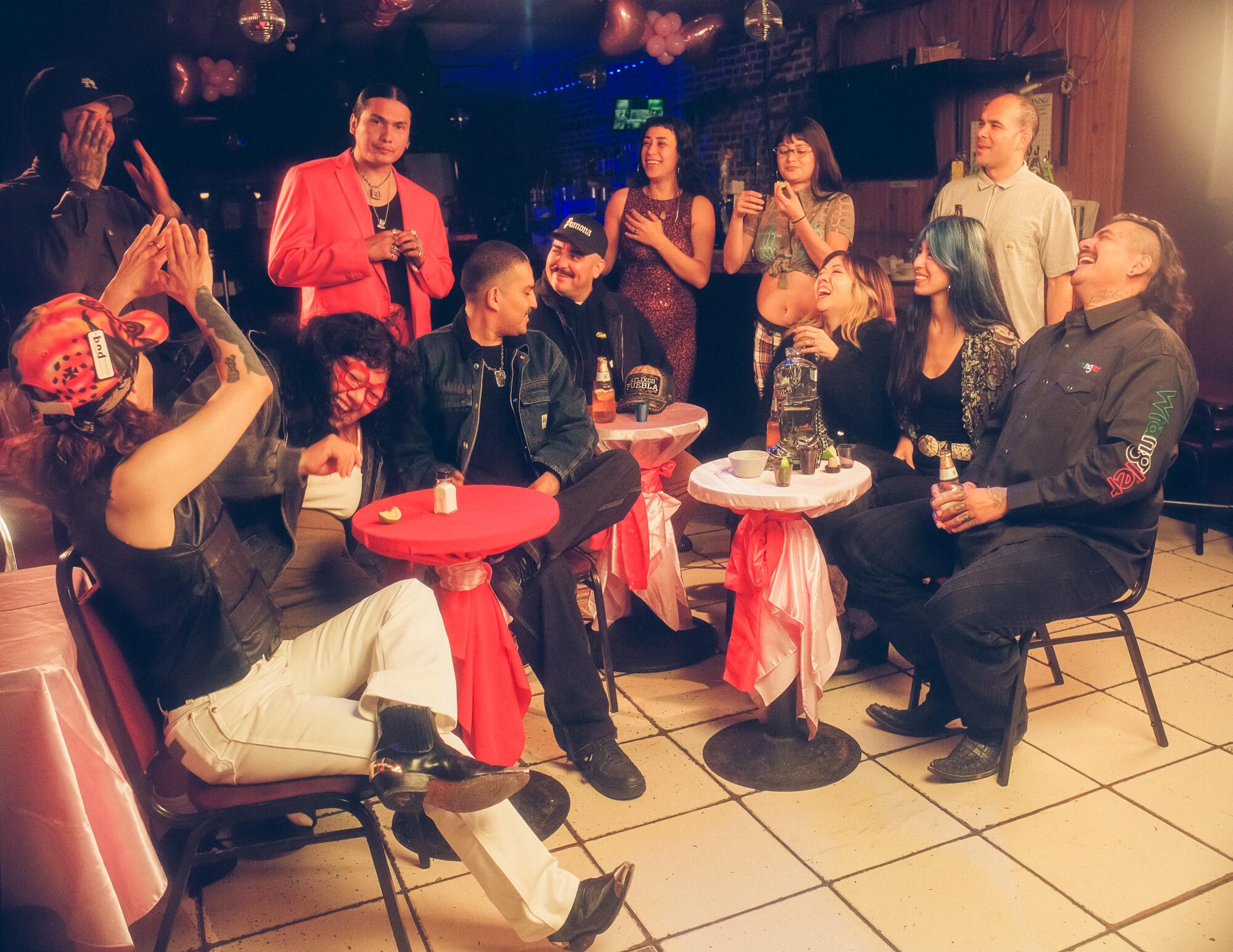 A group of people have fun together around a cluster of tables at a bar.