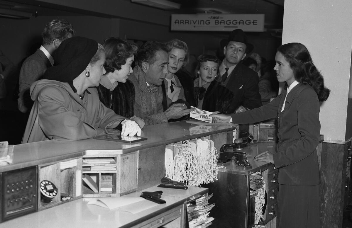 Actors line up at a ticket counter.