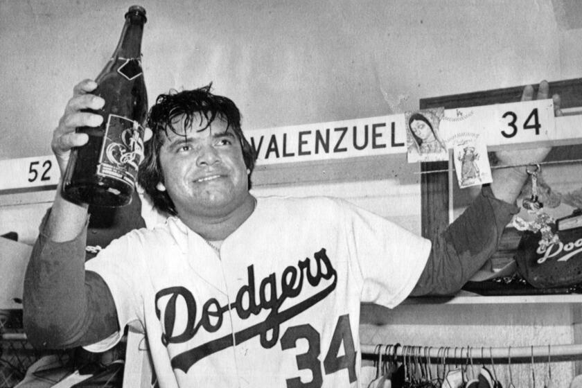 Dodger pitcher Fernando Valenzuela raises a magnum of champagne as the Dodgers toast their NL West victory 