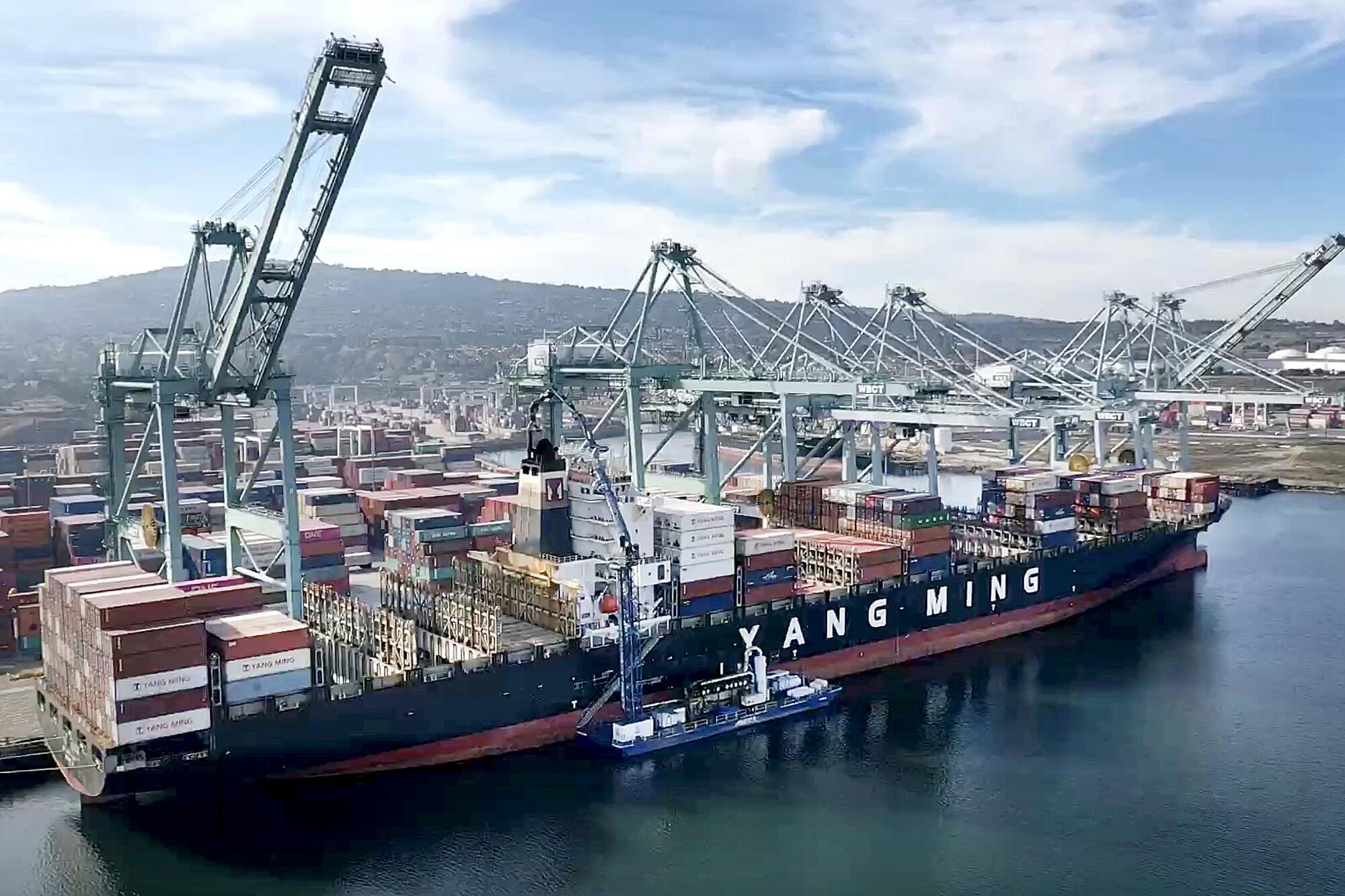 An aerial view of a container ship being unloaded at a port facility.