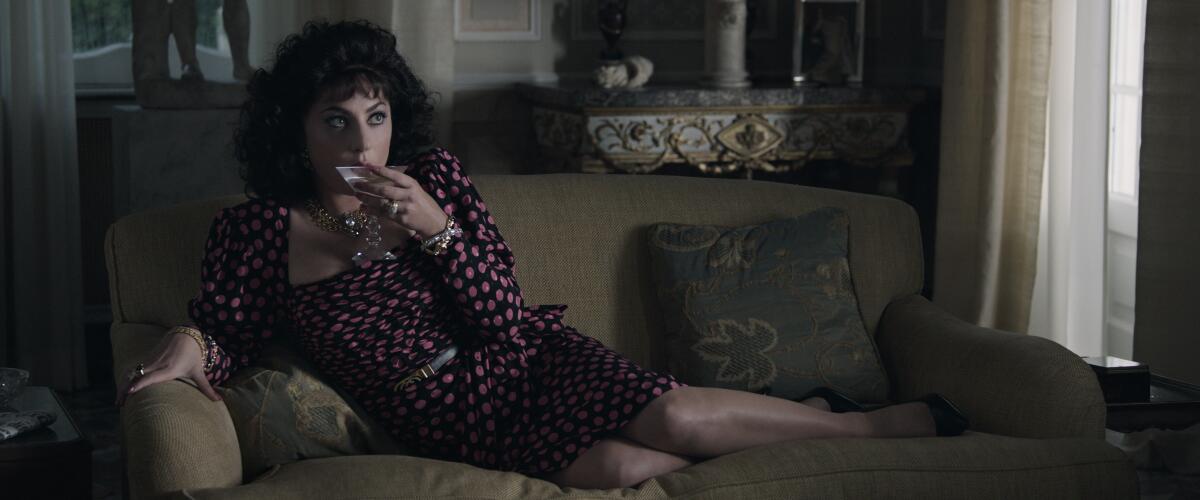 Lady Gaga stars as Patrizia Reggiani sitting on a couch in a "House of Gucci" scene.