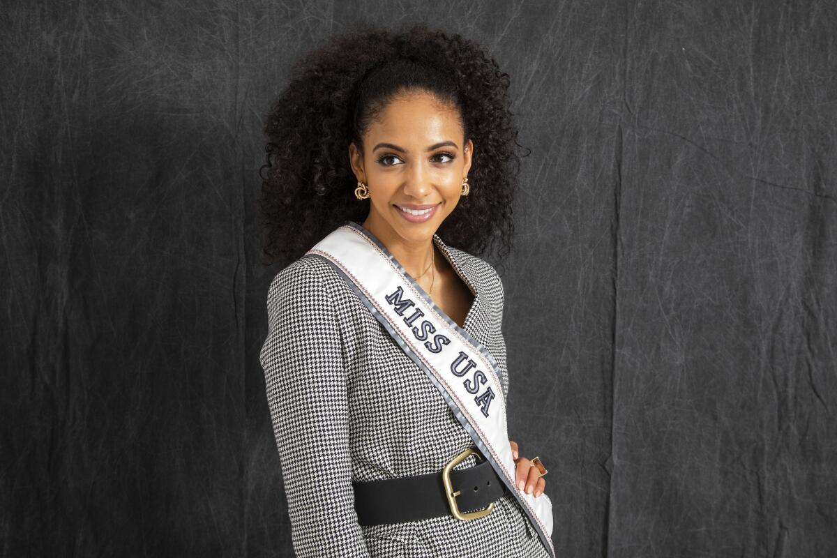 Cheslie Kryst posing in a gingham outfit and "Miss USA" sash.