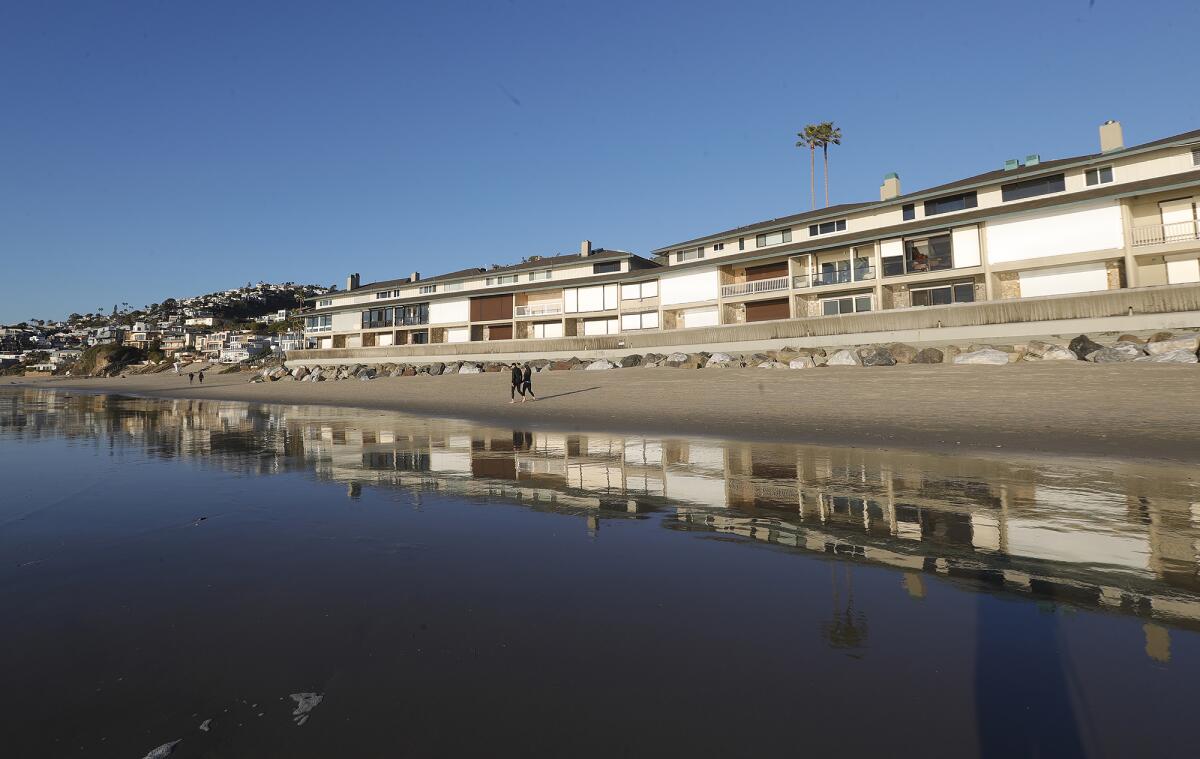 A glass-like surface of exposed wet sand reflects homes on the beach front.