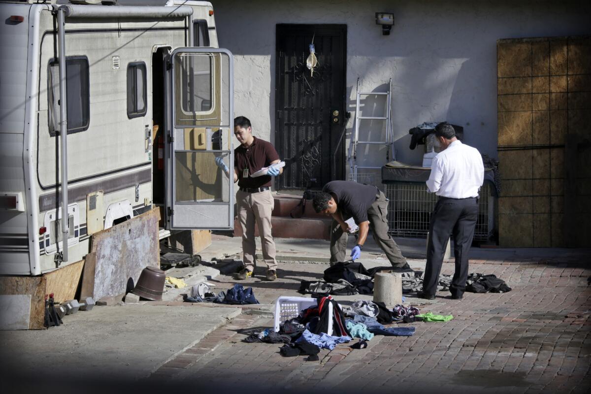 Authorities examine a trailer parked in the backyard of a residence in the 1600 block of East 88th in South L.A., where a 6-year-old boy was found stabbed to death.