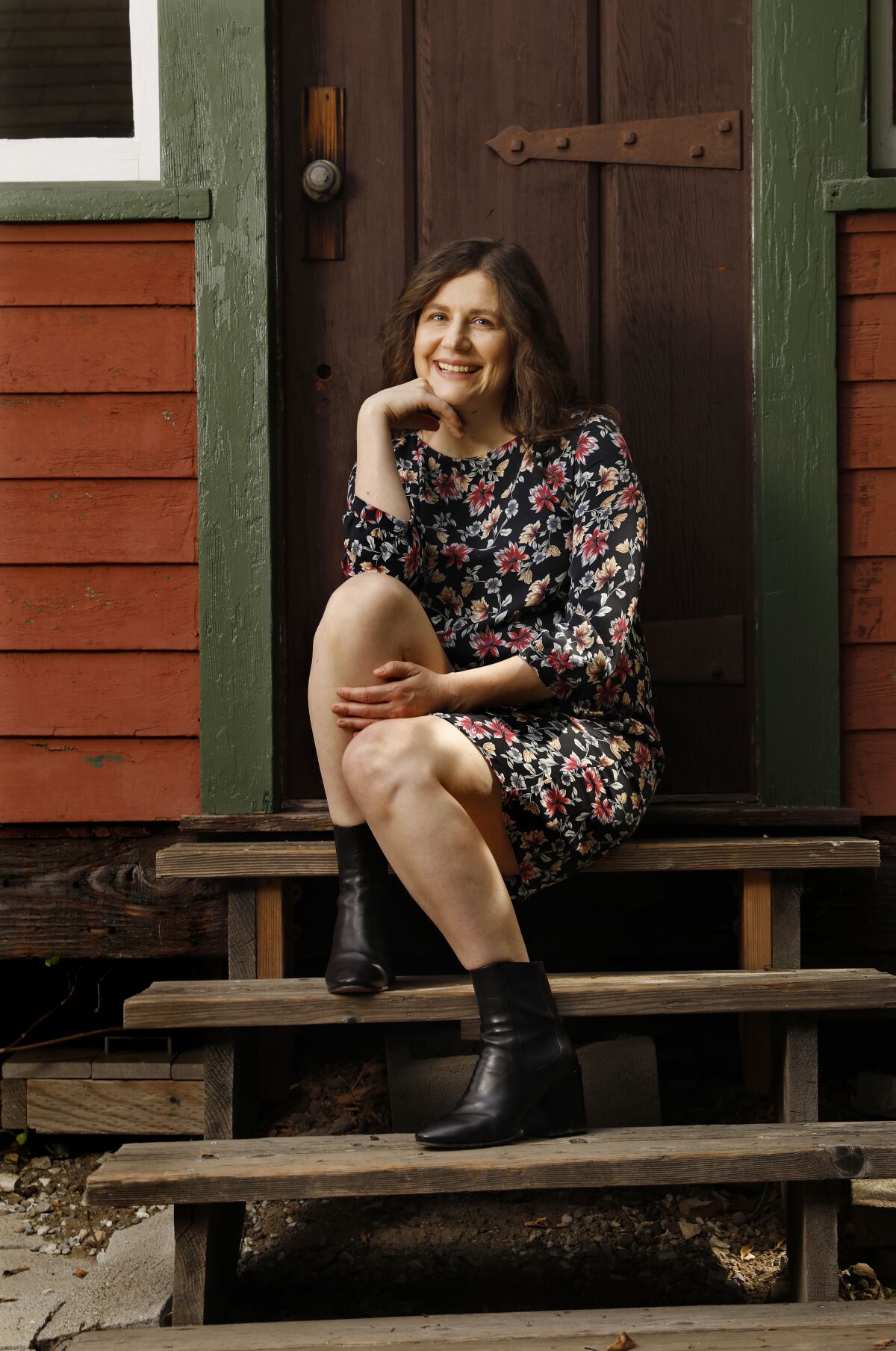  Alena Smith, showrunner of "Dickinson," sits on steps that lead to a door.  